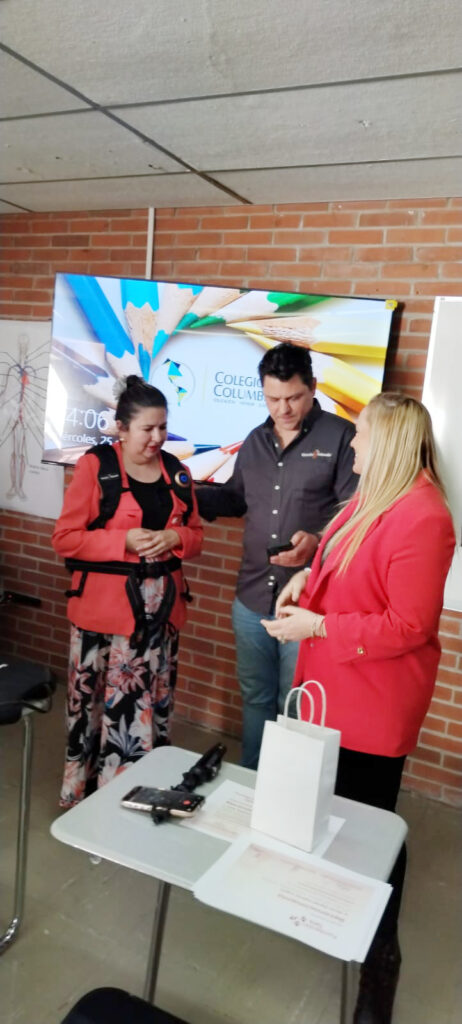 Una persona instructora de Viendo te Entiendo, explica el uso de una tecnología de asistencia a personal docente del Colegio Columbia