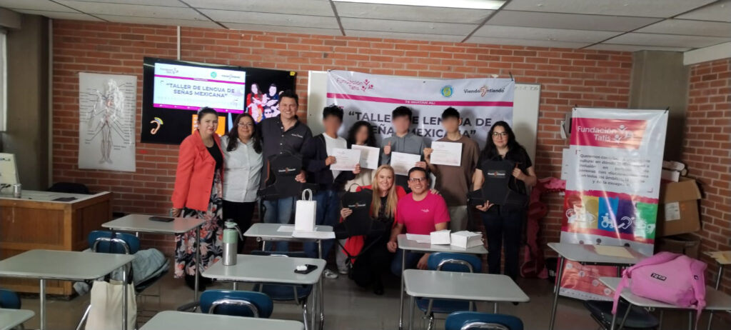 Personas asistentes al talle de LSM y personas instructoras posan frente a la cámara con sus constancias de participación sosteniéndolas en sus manos